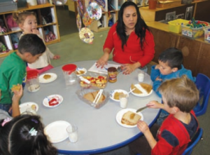 Caregiver eating at the table with five children