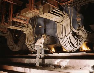 "Alfred A man is operating a large machine that looks like a blast furnace.