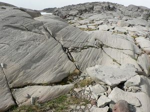 Smoothed polished rock with grooves abraded into them. All of the groves are aligned in the same direction.