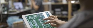 Close up of an engineer examining circuit board on digital tablet