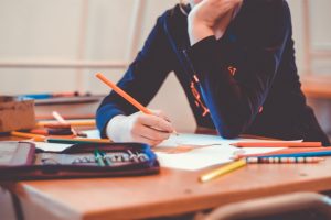 Upper body sitting, writing at desk with pencil and paper