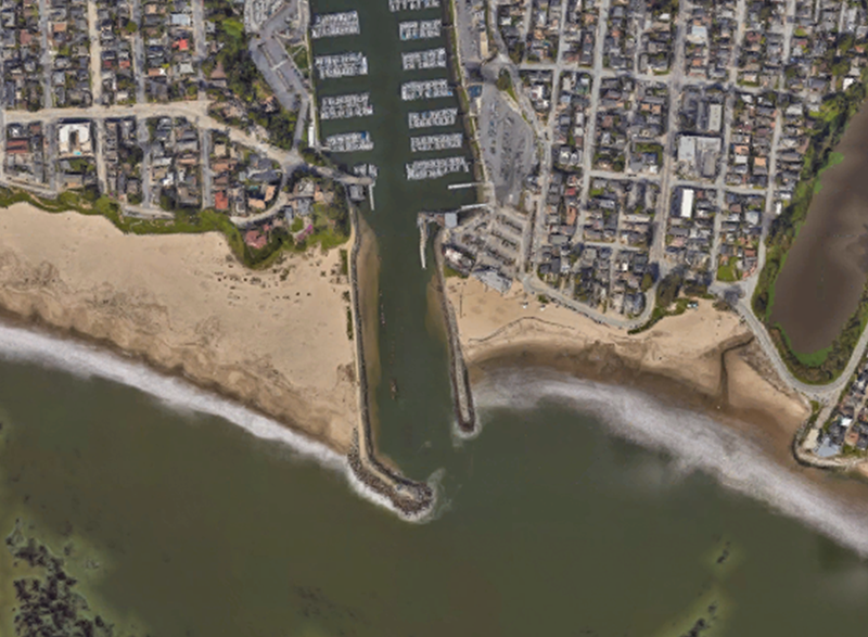 Image of the jetties protecting Santa Cruz harbor, California. Sand has accumulated on the left (north) side of the harbor, and the beach is eroded on the right (south) side.