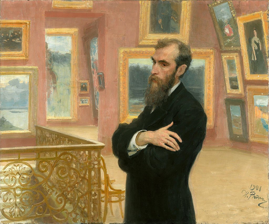 Portait of Pavel Mikhailovich Tretyakov standing in the gallery with arms crossed across his chest with a contemplative look in his face.