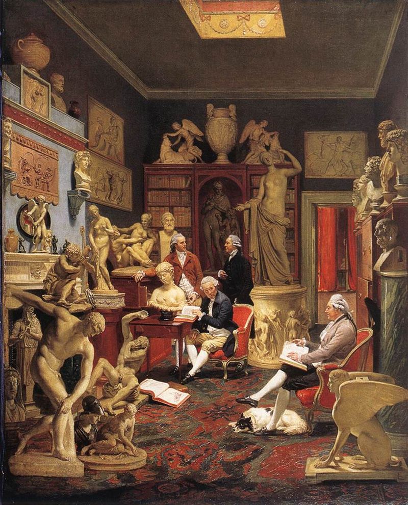 Charles Towneley in his sculpture gallery with three other men surrounded by sculptures. Two are sitting in chairs reading. Two appear to be engaged in conversation.
