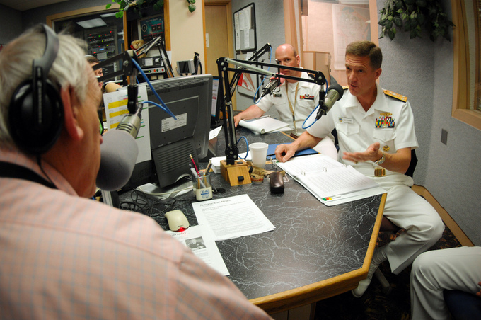 Men in military uniforms speaking with microphones to a radio personality.