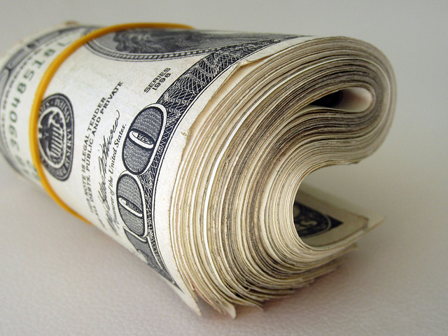 Photograph of a roll of money bound by a rubber band.