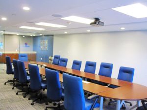 A corporate board room with approximately ten chairs placed around a long table.