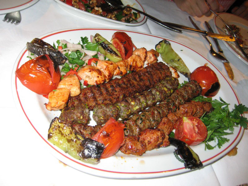 meat kabobs are lying on a bed of vegetables.