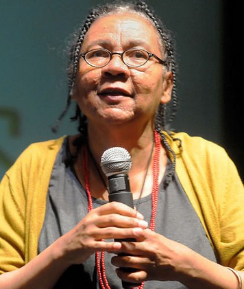 image of bell hooks holding a microphone speaking at an event.