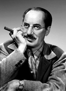 Portrait of Groucho Marx with his hand on his chin holding a cigar.