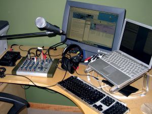 This podcasting setup includes a simple audio mixer, recorder and a computer for recording Skype interviews.