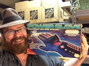A man holds up a Nintendo Power Glove.