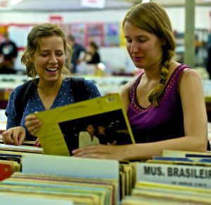 Two women smiling as they browse through vinyl albums.