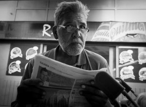 A man glances over his newspaper and his glasses.