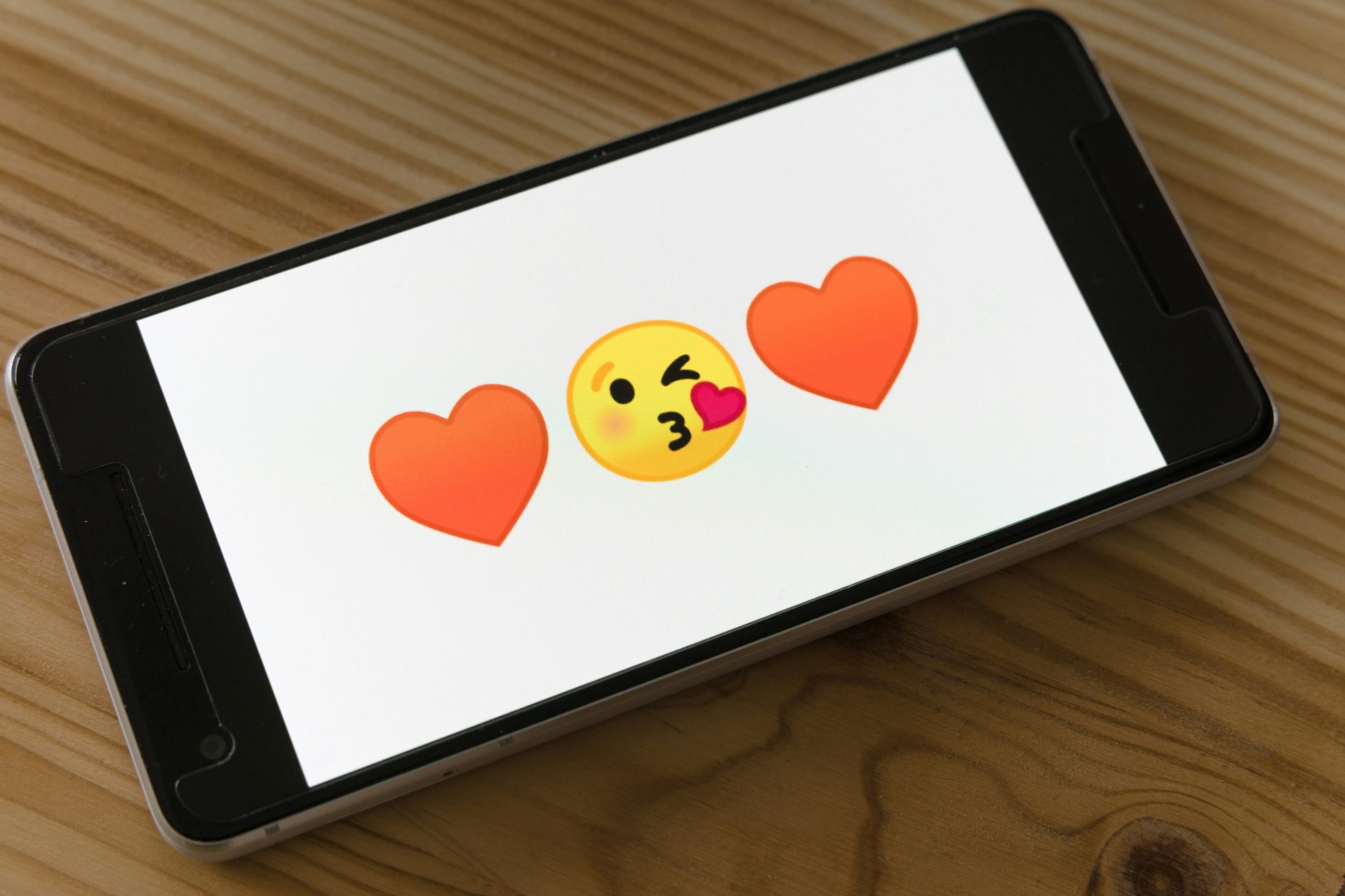 Heart and kiss emojis on a smartphone screen