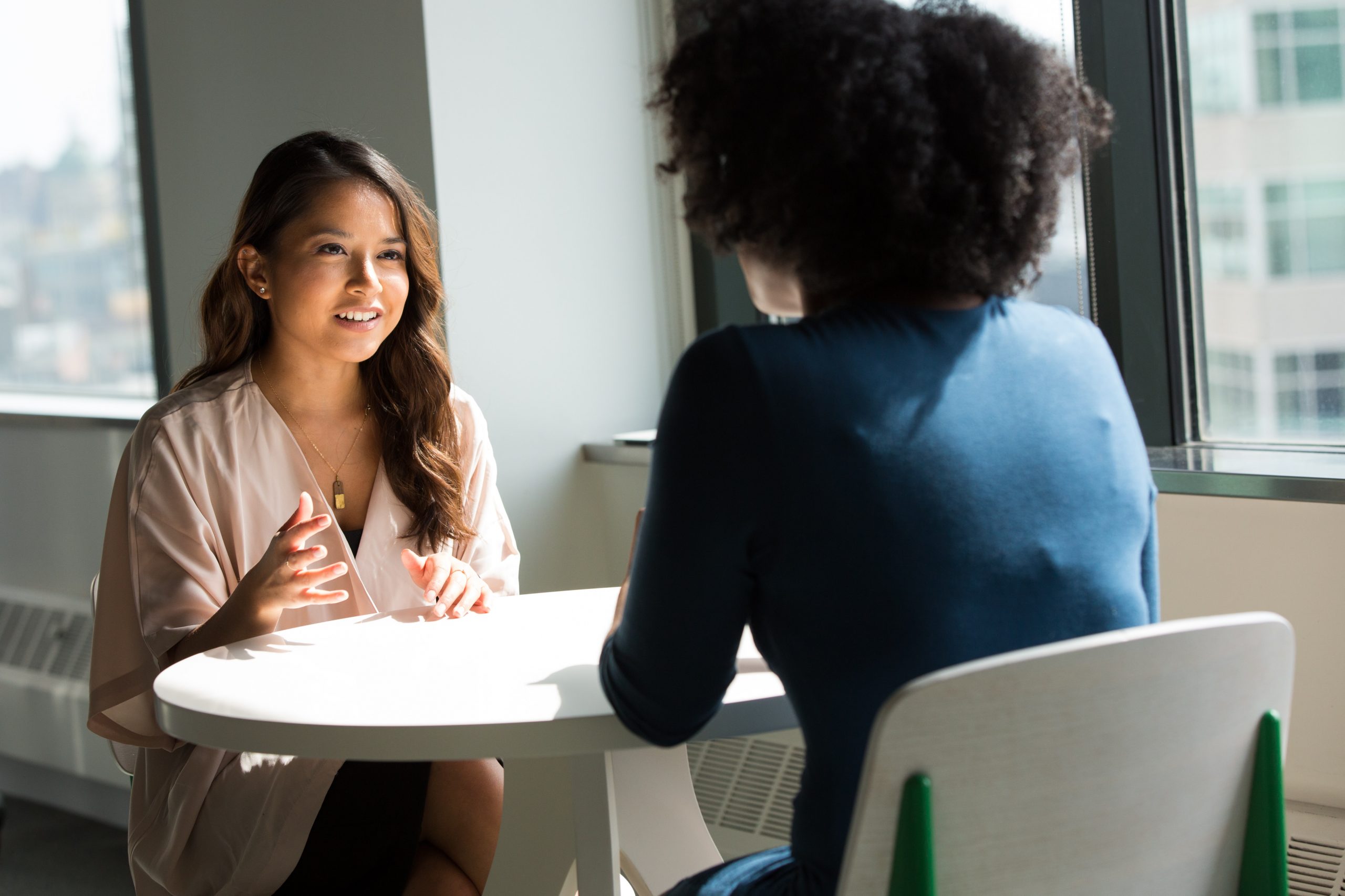 Two business women talking at a table.