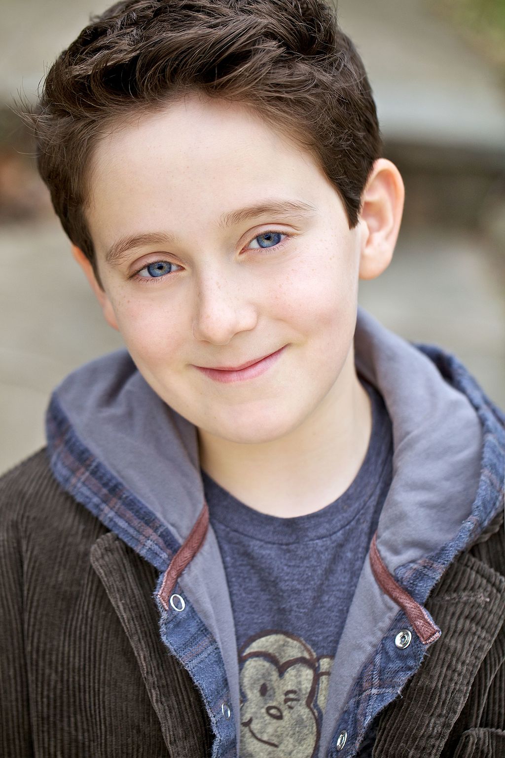Portrait of boy with brown hair and blue eyes smiling at the camera.