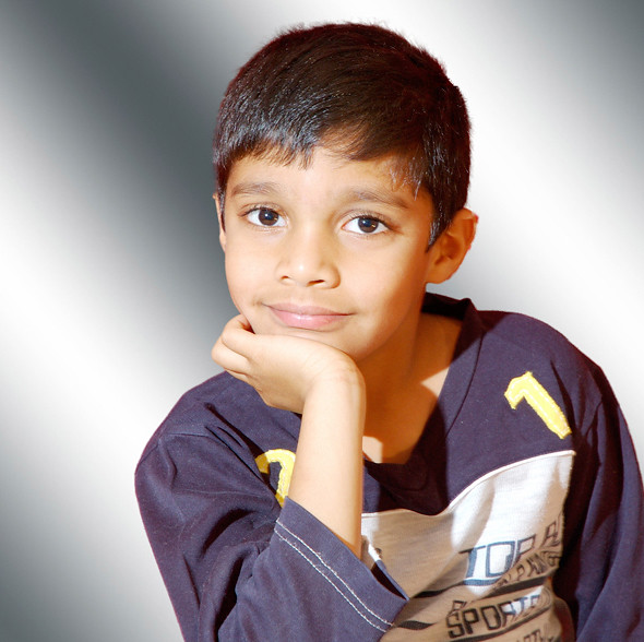 Portrait of a boy with brown hair and brown eyes wearing a sports shirt, smiling at the camera.