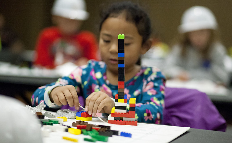 Block building competition. Girl building Lego tower.