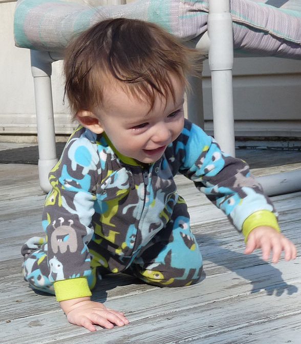 Baby in a onesie crawling.