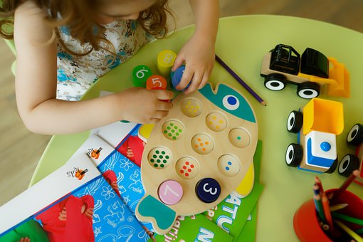 Young girl playing with a fish that teaches children how to count by placing blocks matching the number of dots in the circle.