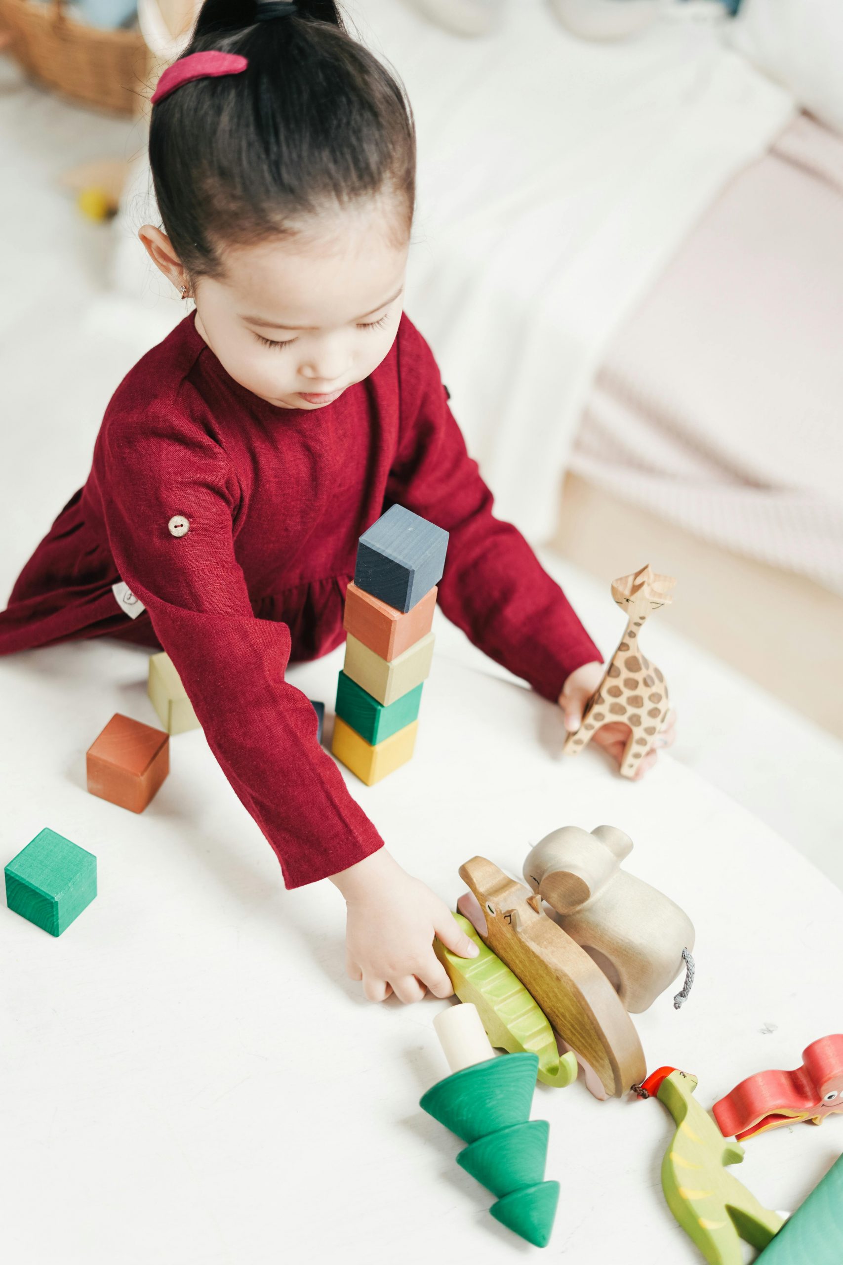 Child in red dress playing with wood blocks.