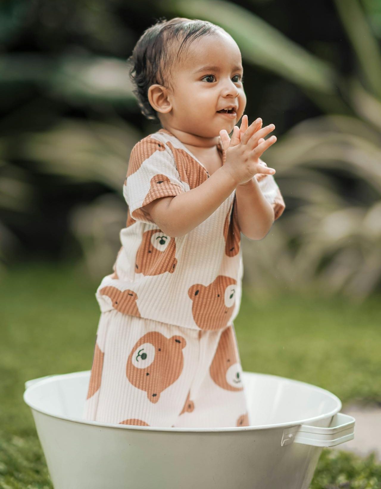 Toddler wearing a bear pajamas standing and clapping their hands.