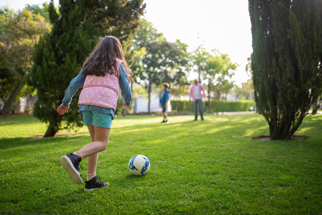 Backview of a girl kicking a soccer ball.