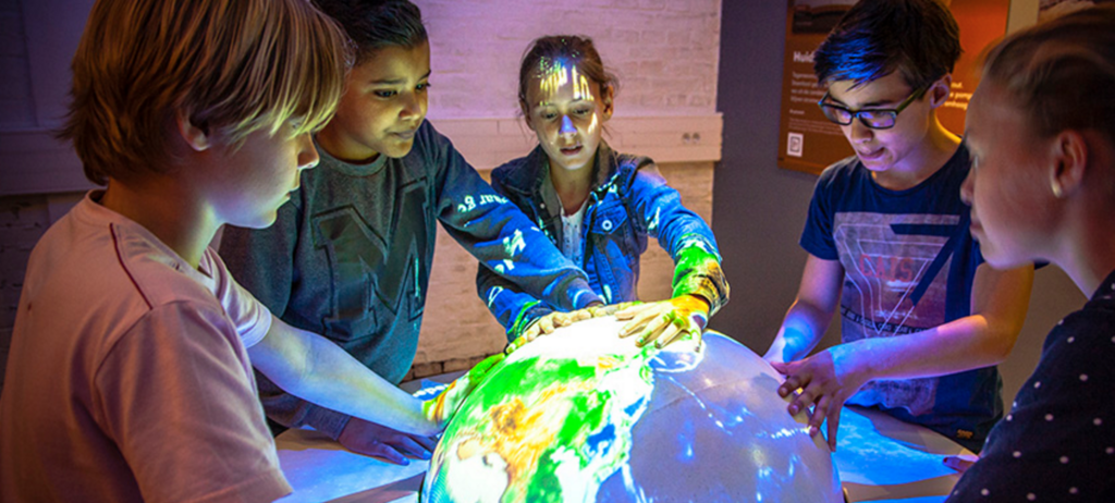 Children in a classroom viewing a globe that is illuminated.