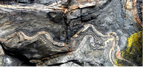 Grey limestone rock with waves of beige and green.