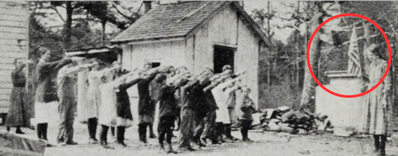 Photograph of school aged children saluting the American flag in the early 1900s