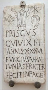 A robed man in prayer position, a man’s head and a dove with an olive branch. The initials Rho and Chi are presented one on top of the other.