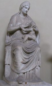 A marble carving of a Roman goddess breastfeeding her child. She is naturalistic, seated and fully clothed.