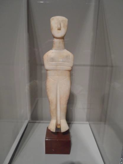 Small, simple sculpture of a female figure carved from white stone.