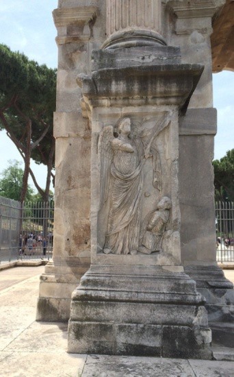 A winged figure towers over a kneeling person.