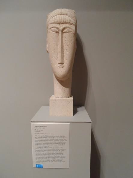 A modern sculpture of a simplified head with a long nose and face.