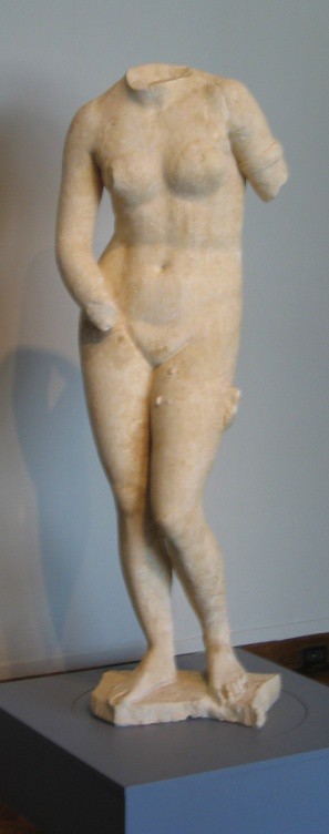 A headless marble statue of Venus whose left arm and right hand are now missing. She is tall and thin and posed like the Aphrodite of Praxiteles.