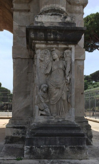 A bearded man kneels at the feet of a winged figure.