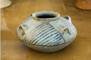 Small squat pot with stripes and a small opening at the top.