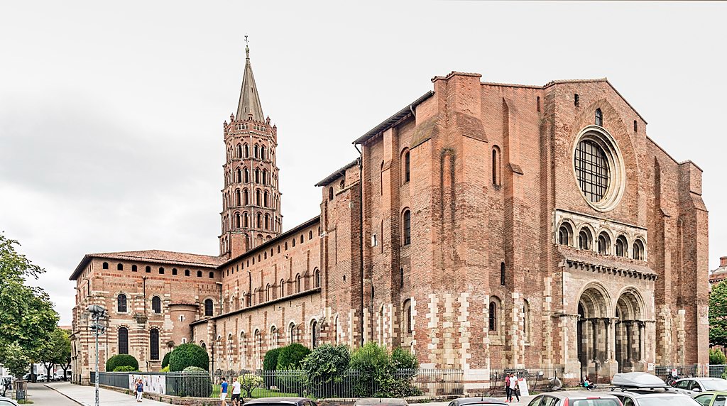 A massive church made of stone in a cross-shape. A tower is centered over the crossing of the transept and the nave.