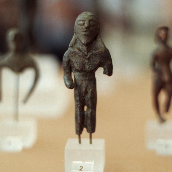 A crude casting in bronze of a charioteer. The focus is on the head and it is not naturalistic.