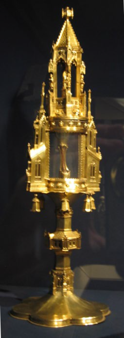 A gold container that looks like a church containing a fingerbone.