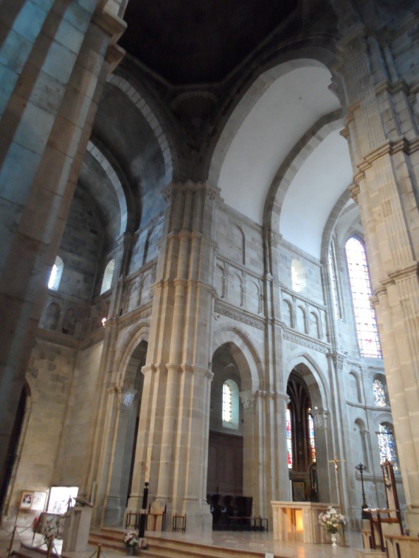 The interior of a large Romanesque church with both pointed and round arches. Light comes in through the rebuilt Gothic Apse.