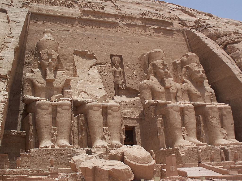 The Temple of Ramses with two enormous statues of the king sitting on each side of the door. Smaller statues stand between the lower legs of the larger ones. The statues are idealized.