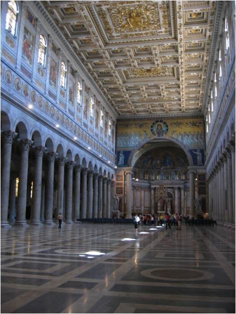 A photo of the interior of the church from the viewpoint of the narthex. The coffered ceiling, enclosed apse and marble floor are presented.