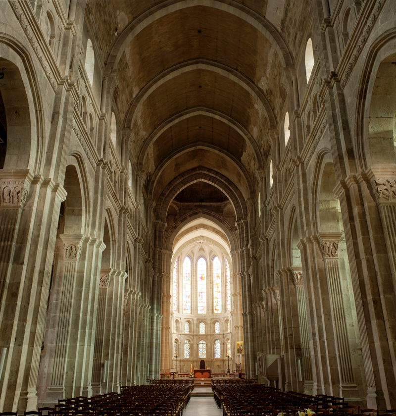 A typically dark view of the nave but a lot of light comes through the apse which has gothic additions of stacked, tall pointed arch shaped windows.