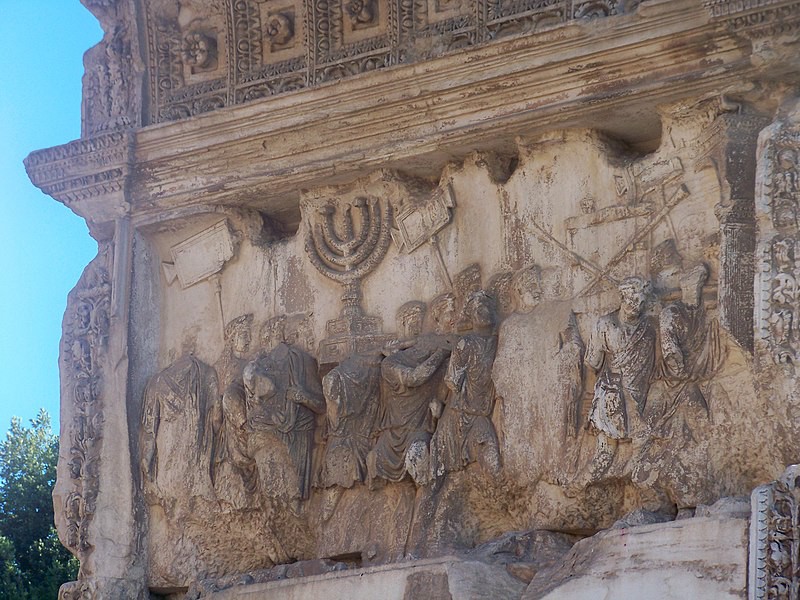 A detail of the arch carving that presents Titus’ troops bringing home loot, including a minora.