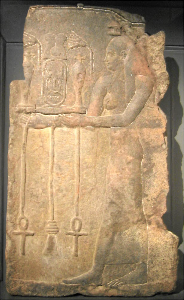 Carved image of the Nile Goddess Hapi. She carries lotus blossoms, and water vessels on a tray with ankhs and died hanging from it.