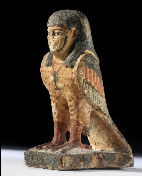 A painted statue of a bird with a human face.