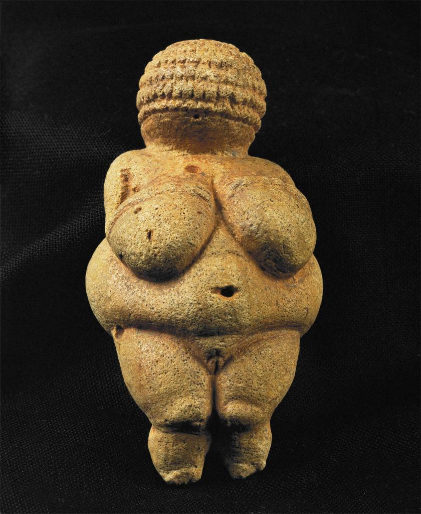 A small stone carving of a woman with no feet or face.